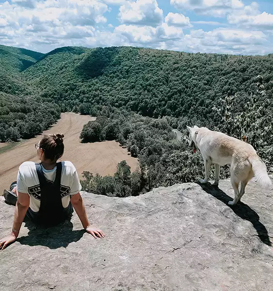 woman and dog looking over a mountain cliff